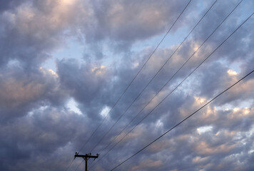 Utility pole and high voltage power supply lines against sky and clouds in Wyoming	
