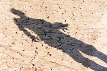 Shadow of a photographer on a dry and cracked ground