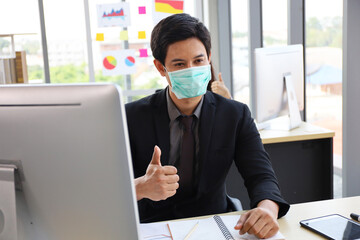 Business people or office worker are working and thumbs up and wear mask for protect Covid-19 or corona virus disease but business must be continuous, healthcare concept 