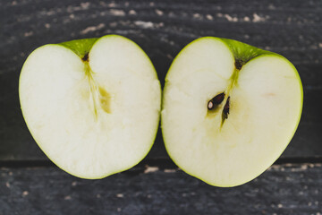food ingredients concept, green apple cut in half on wooden table