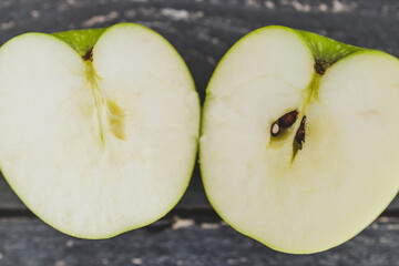 food ingredients concept, green apple cut in half on wooden table