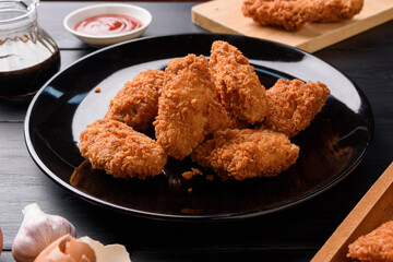 Fried breaded chicken wings on wooden table. Close up 