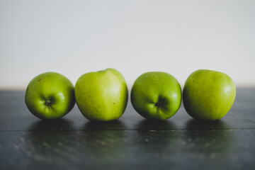 food ingredients concept, green apples lined up on wooden table shot from eye-level perspective