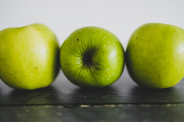 food ingredients concept, green apples lined up on wooden table shot from eye-level perspective