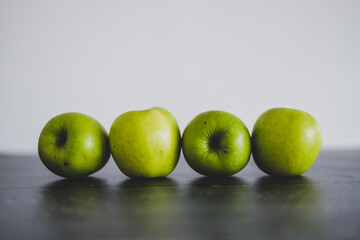 food ingredients concept, green apples lined up on wooden table shot from eye-level perspective
