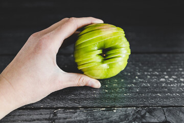 food ingredients concept, hand holding green apple cut into thin equal slices stacked to maintain...