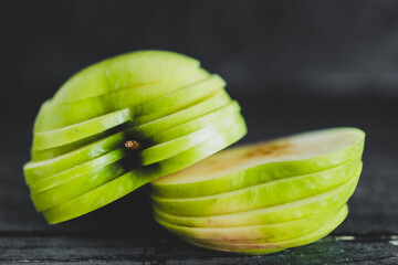 food ingredients concept, green apple cut into thin equal slices stacked into two halves