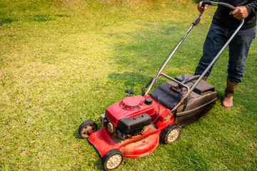 A man cutting the grass with a lawn mower