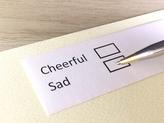 One person is answering question on a piece of paper. The person is thinking to be cheerful or to be sad.