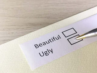 One person is answering question on a piece of paper. The person is thinking to be beautiful or ugly.