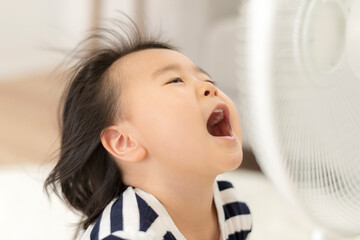 自宅のリビングで扇風機の風にあたって「あ〜」と言っている女の子
