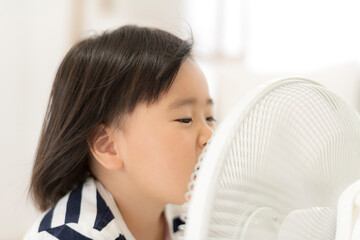 自宅のリビングで扇風機の風にあたって「あ〜」と言っている女の子