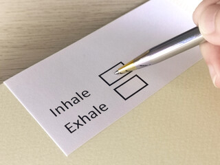 One person is answering question on a piece of paper. The person is thinking to inhale or to exhale.
