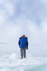 Fototapeta na wymiar A man doing solo outdoor activity, enjoying time alone in nature, walking on frozen lake in winter