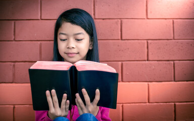 Happy asian young girl learning and reading to the holy bible, religion christian concept.