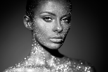 Fashion model woman in bright sparkles and lights posing in studio. Portrait of beautiful sexy...