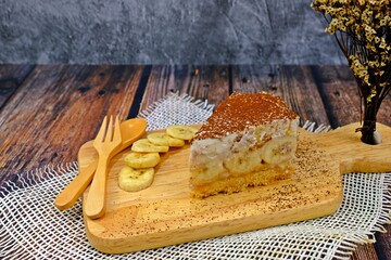 Bannofee pie served on wooden tray decorated with banana slices on wooden table.