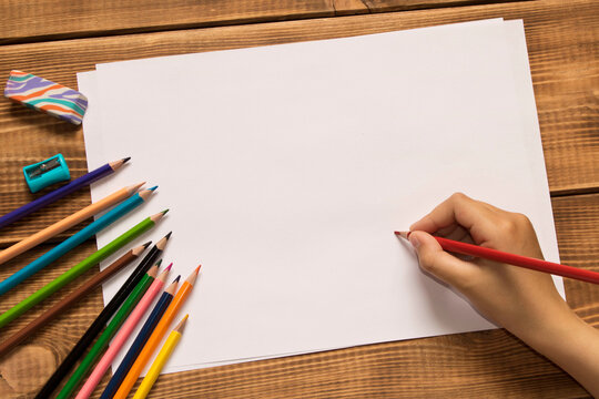 The girl draws with colored pencils. Close up.