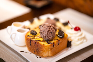 Chocolate Honey Toast, sweet food menu which is served on the table. Close-up and selective focus at the chocolate ice cream white blurred other topping.
