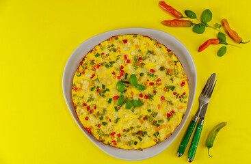 Cauliflower omelette with fork and knife on yellow background.