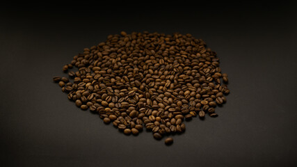 Background from a dense layer of brown roasted coffee. Fresh fragrant dark grains for bitter drink.