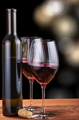 two glasses and bottle with red wine on black