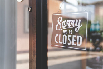 Label 'Sorry we're closed' notice sign wood board hanging on door front coffee shop.