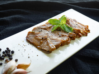 Grilled pork,Ingredients garlic, pepper,Place on a white plate,sprinkle with pepper,Decorate the face with mint leaves,Thai food