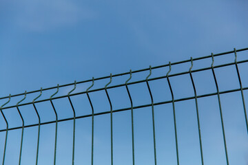 Steel grill fence with wire against the blue sky