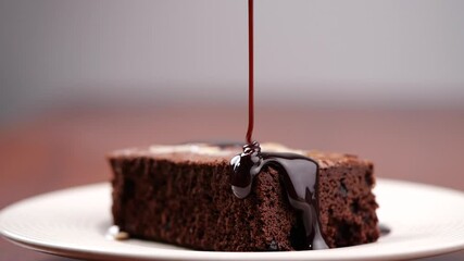 Chocolate pouring on cake in slow motion. Topping chocolate on homemade brownie dessert