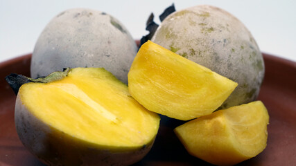 Persimmon or kesemek on pottery plate on white background. The fruit is covered by white flour after immersing in water with calcium oxide to remove tannin.