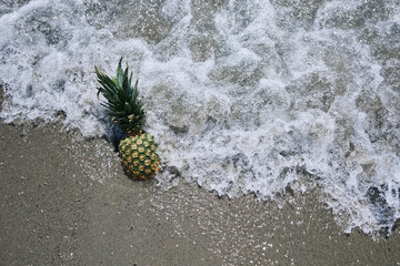 a pineapple on the beach is hit by the waves of the sea