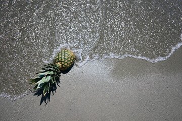 a pineapple on the beach is hit by the waves of the sea