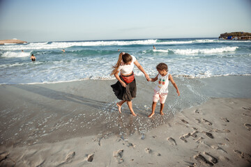 Family walking on the evening beach during sunset. Child with mom.