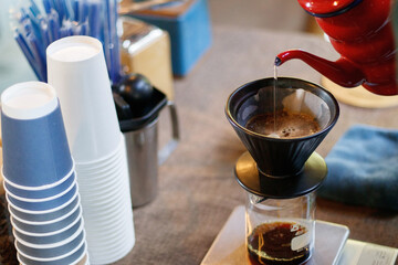 Barista pouring water over ground coffee beans contained in a filter.