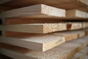 Stack of natural rough wooden boards close-up. Storage of wood in a carpenter's workshop or at a sawmill