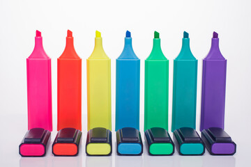 Office supplies concept. Photo of multicolored highlighter set with caps beside isolated on white...