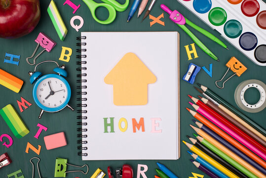 Studying at home concept. Top above overhead view photo of blank notebook with home letters and house shaped note and colorful stationery isolated on greenboard