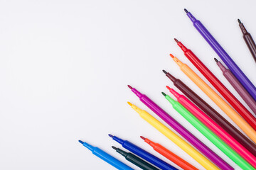 Drawing supplies concept. Top above overhead view photo of colorful markers with caps off placed to the right side isolated on white background
