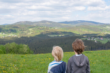 Fototapeta na wymiar Two boys watching beautiful view, mountain landscape, standing backwards, mountain holidays