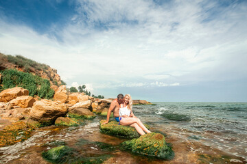 love couple sitting on a rock in the ocean. Beautiful life, positive energy and invitation to relax and meditation. Summer and beach concept