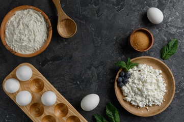 Cottage cheese, flour, eggs, sugar. Dark background.