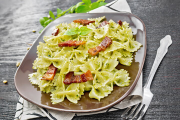 Farfalle with pesto and bacon on dark board