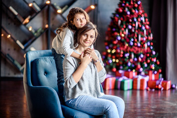 Naklejka premium Mother and Child Hug in Front of a Christmas Tree.