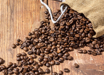 Coffee beans spilled from a bag on a wooden surface