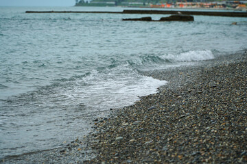 Surf. Waves at the stone beach. Shore of the cold sea. Grey sky and ocean. High quality photo