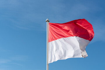 Naklejka na ściany i meble Monaco's flag Raise on blue sky high background.