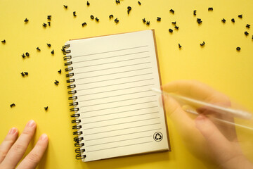 Notepad notebook, 3d black letters and hands on yellow background. concept back to school, writing...