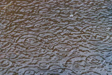 Puddle of water with splashing raindrops during a downpour