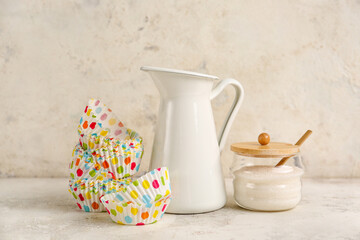 Muffin baking cups with products on light background